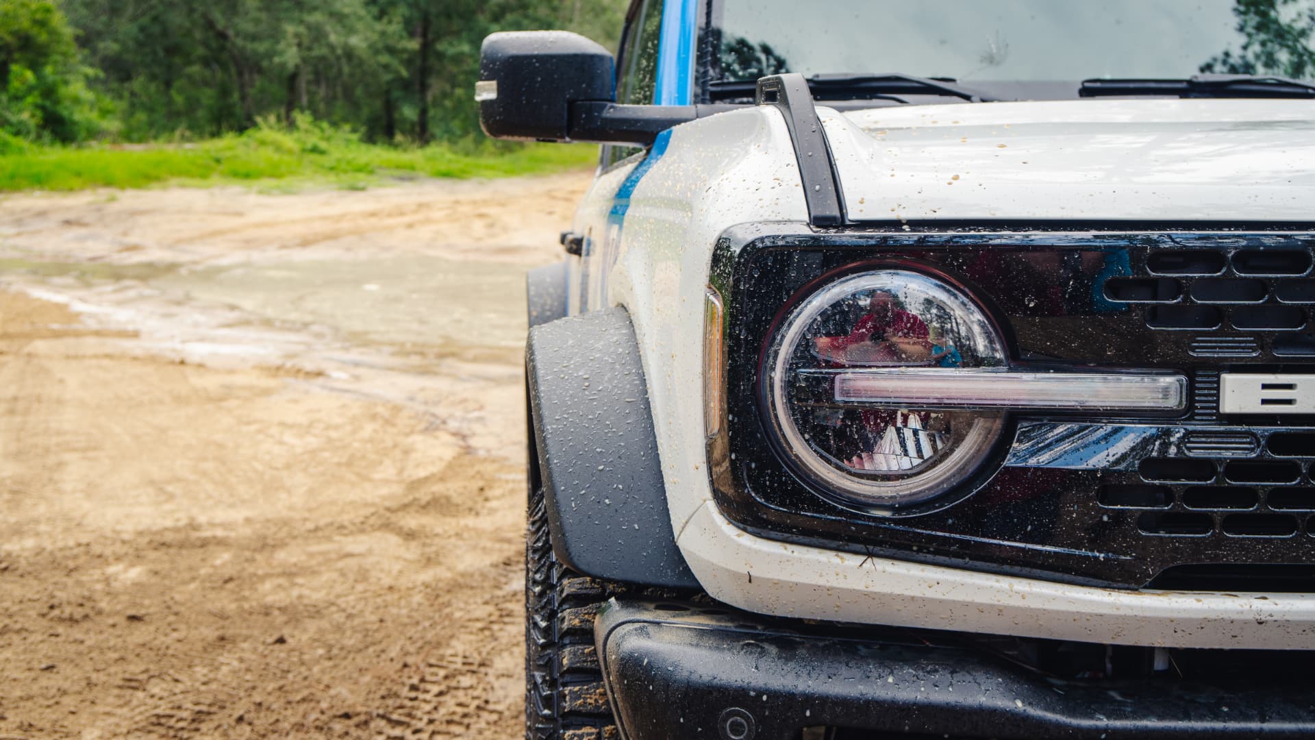 Close up of the muddy front headlight and grille of the Bronco Wildtrak after a trail run