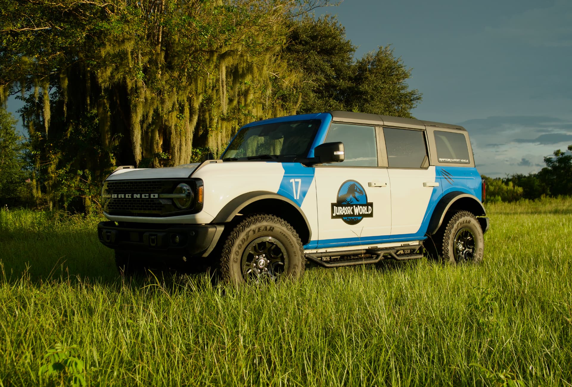 2023 Ford Bronco Wildtrak with Jurassic World wrap parked in tall grass under Spanish moss
