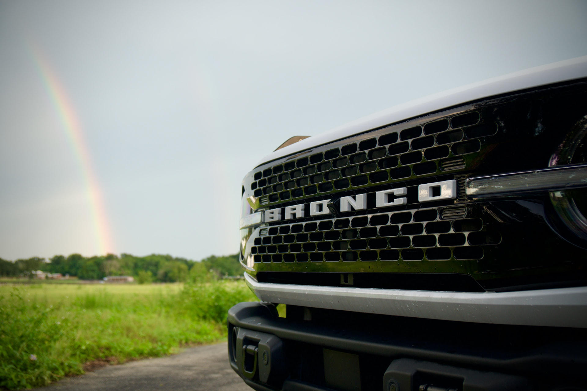 Close up of the Ford Bronco grille with a rainbow in the distance